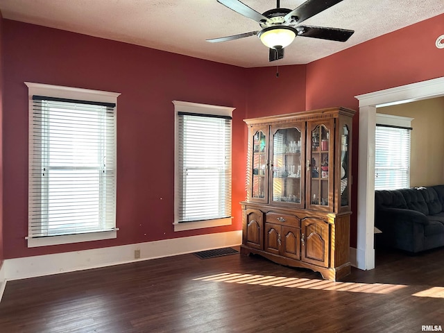 interior space featuring dark wood-style floors, visible vents, a textured ceiling, and a ceiling fan