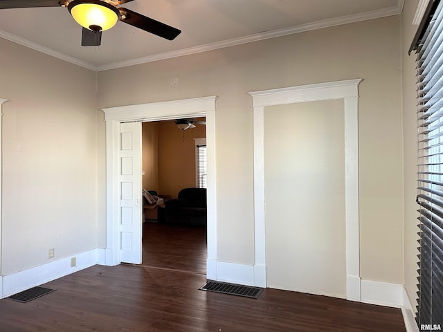 empty room with dark wood-style flooring, visible vents, ornamental molding, a ceiling fan, and baseboards