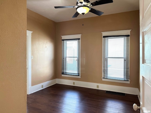 empty room featuring baseboards, visible vents, a ceiling fan, a textured wall, and dark wood-style floors