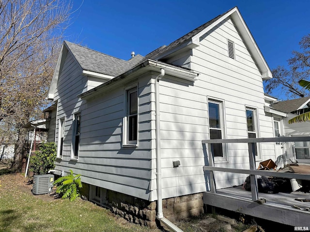 view of home's exterior with roof with shingles, a wooden deck, and central AC unit