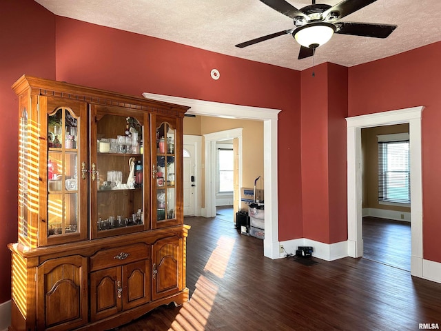 hall featuring dark wood finished floors, a textured ceiling, and baseboards