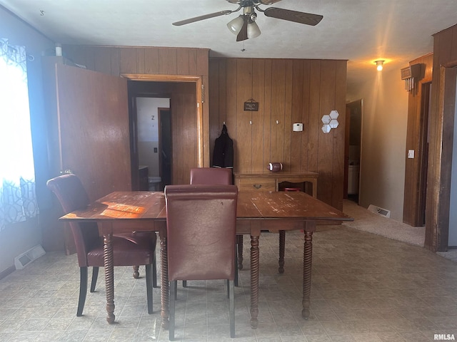 dining room featuring ceiling fan and wood walls