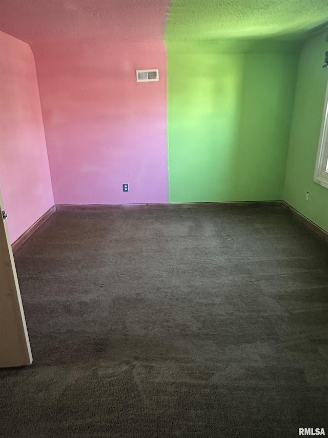 spare room with carpet flooring, visible vents, and a textured ceiling