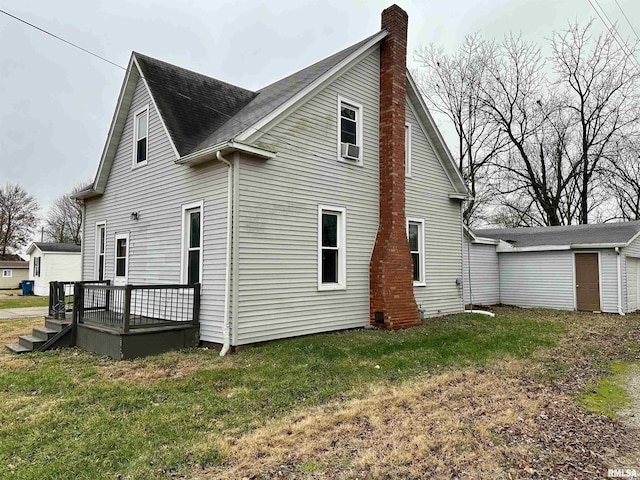 back of house featuring an outbuilding, a lawn, a deck, a shed, and a chimney