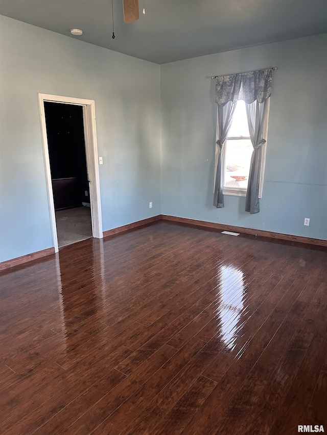 empty room featuring hardwood / wood-style flooring, visible vents, baseboards, and ceiling fan