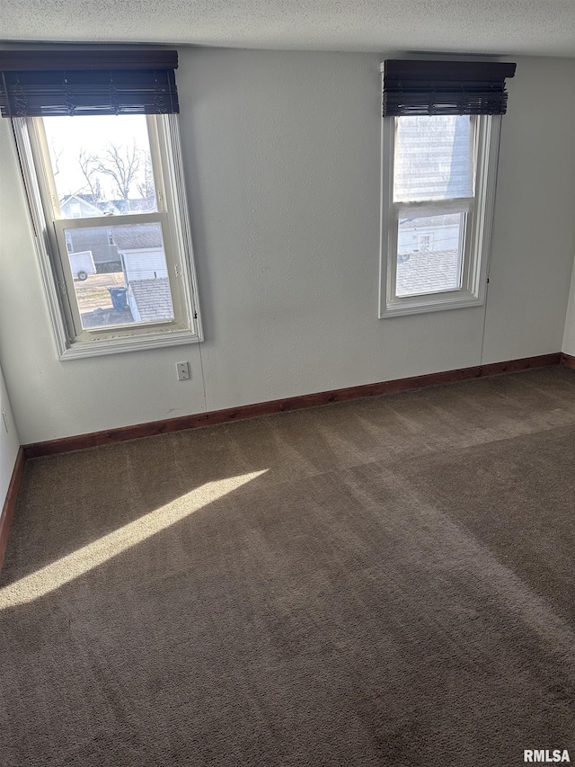 unfurnished room featuring a healthy amount of sunlight, a textured ceiling, baseboards, and carpet floors