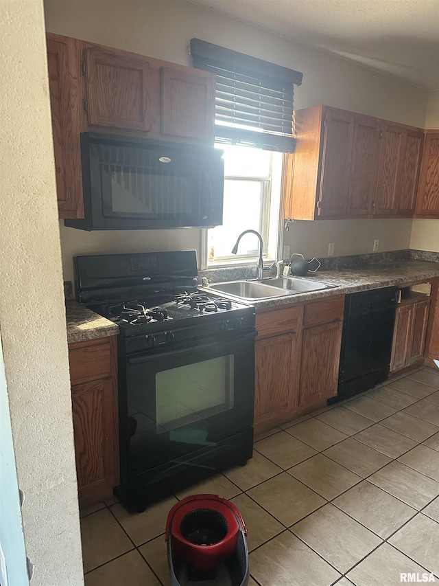 kitchen with a sink, brown cabinets, black appliances, and light tile patterned floors