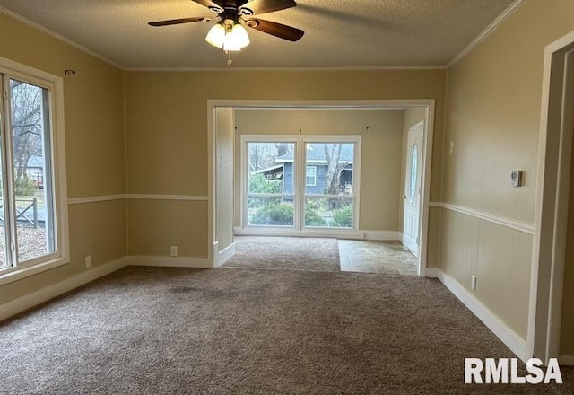 empty room featuring a wealth of natural light, a textured ceiling, light colored carpet, and ceiling fan