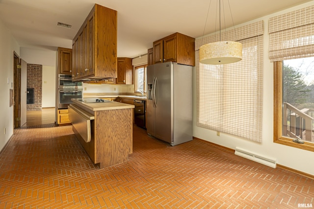 kitchen with black appliances, sink, hanging light fixtures, a brick fireplace, and a kitchen island