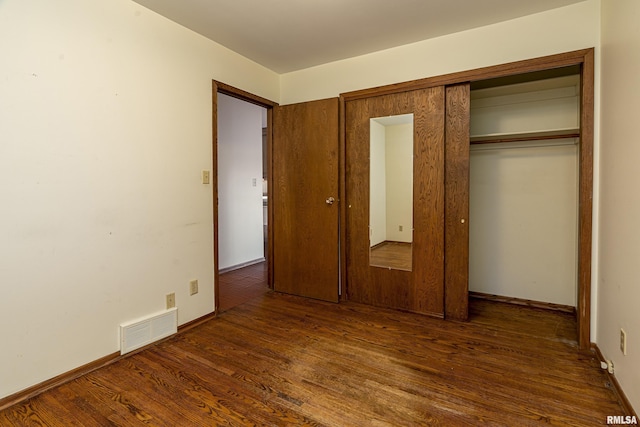 unfurnished bedroom with dark hardwood / wood-style flooring and a closet