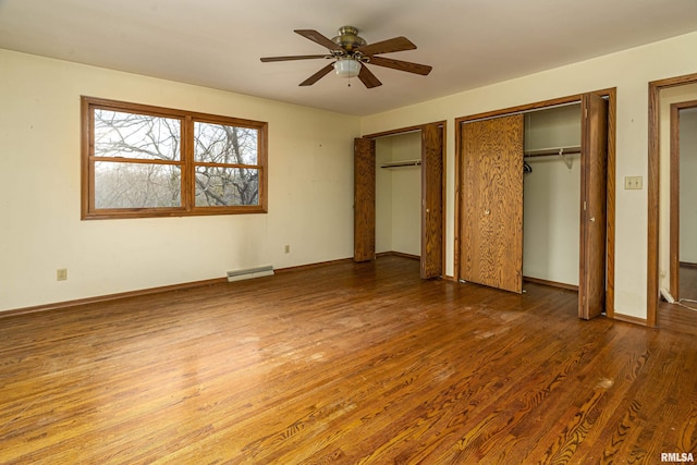 unfurnished bedroom with two closets, ceiling fan, and dark wood-type flooring