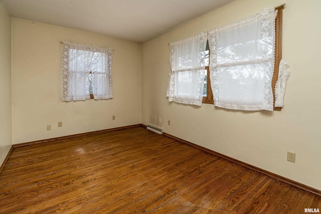 spare room with hardwood / wood-style floors and a baseboard heating unit