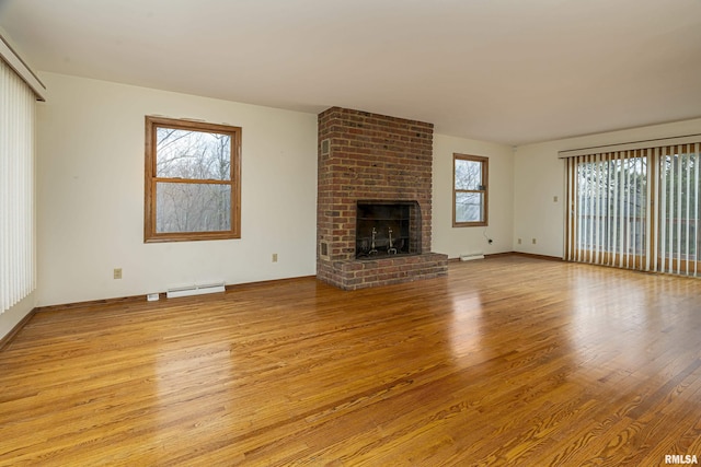 unfurnished living room with a fireplace, light hardwood / wood-style floors, and a baseboard heating unit