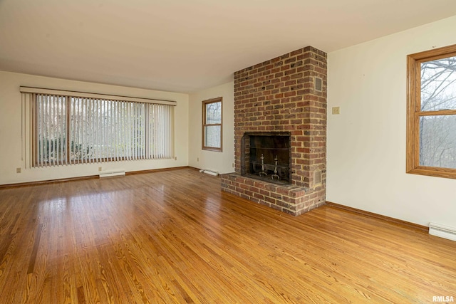 unfurnished living room featuring a fireplace, light hardwood / wood-style flooring, and a healthy amount of sunlight