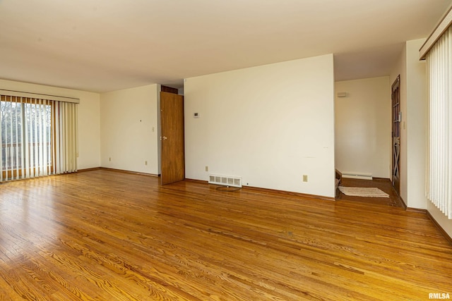 spare room with baseboard heating and light hardwood / wood-style flooring