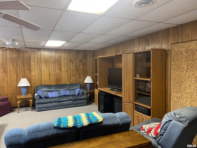 living room with carpet flooring, a paneled ceiling, ceiling fan, and wooden walls