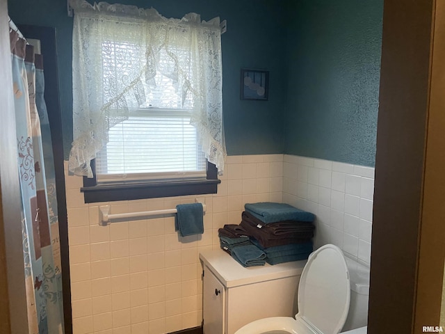 bathroom with toilet and tile walls