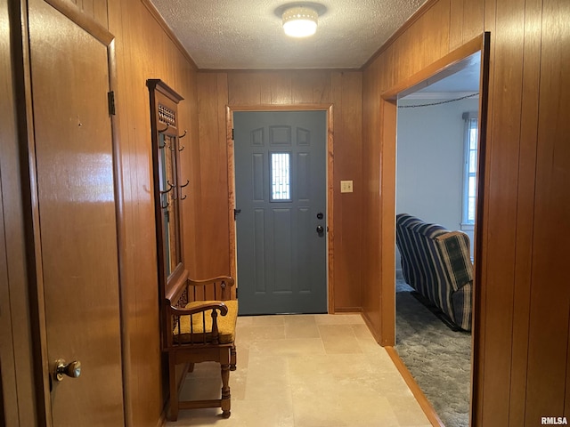 entryway featuring a textured ceiling and wooden walls