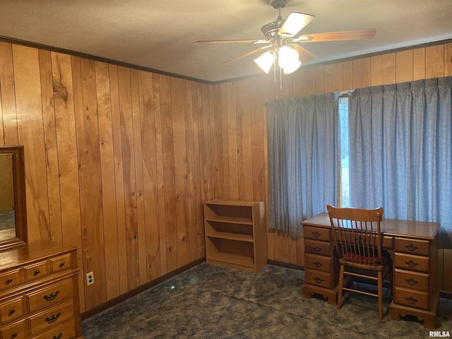 carpeted office space featuring ceiling fan, wood walls, and ornamental molding