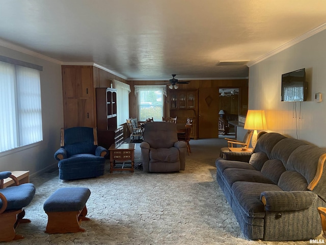 carpeted living room with wooden walls, ceiling fan, and ornamental molding