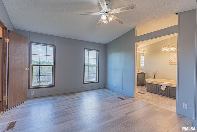 408 W Kirkwood St, Odin, IL 62870 - unfurnished bedroom featuring light wood-style floors, a textured ceiling, a chandelier, vaulted ceiling, and connected bathroom