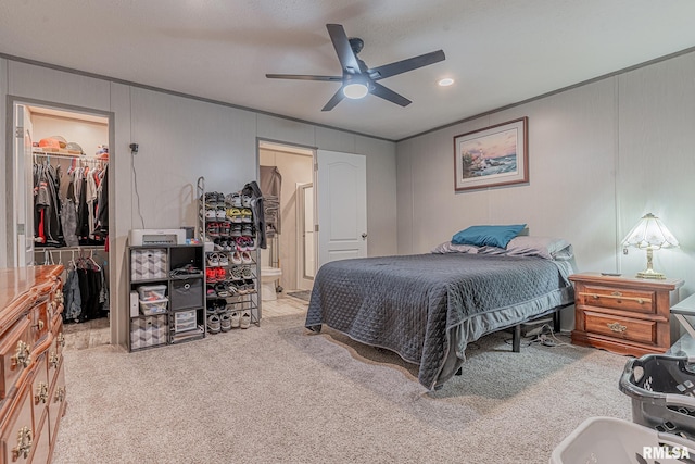 bedroom featuring ensuite bath, light colored carpet, ceiling fan, a spacious closet, and a closet