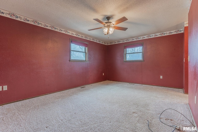 carpeted empty room with ceiling fan and a textured ceiling