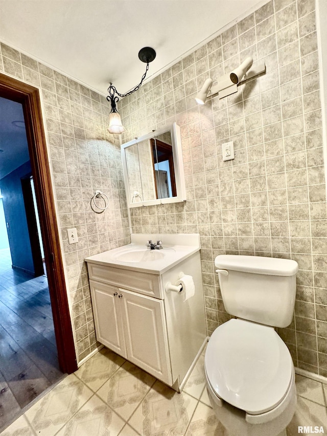 bathroom featuring vanity, toilet, and tile walls