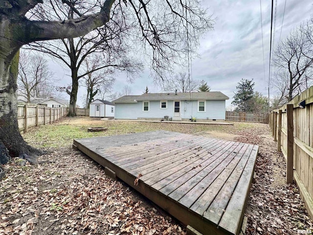 rear view of property featuring a storage shed and a wooden deck