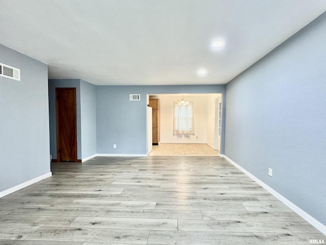 unfurnished living room with light hardwood / wood-style floors and a chandelier