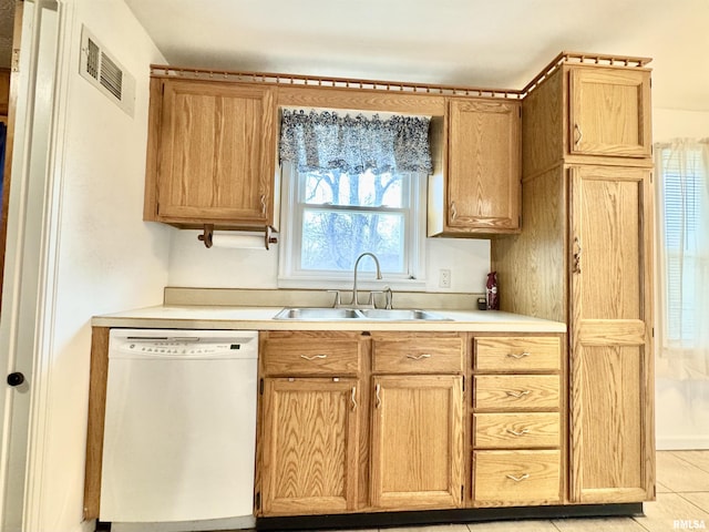 kitchen featuring sink, white dishwasher, and light tile patterned flooring