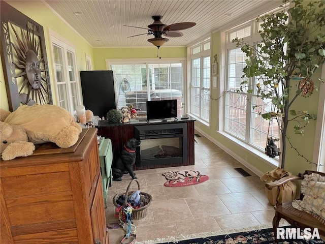 sunroom / solarium with ceiling fan, wood ceiling, and a fireplace