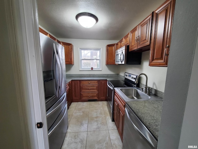 kitchen featuring light tile patterned floors, a textured ceiling, stainless steel appliances, and sink