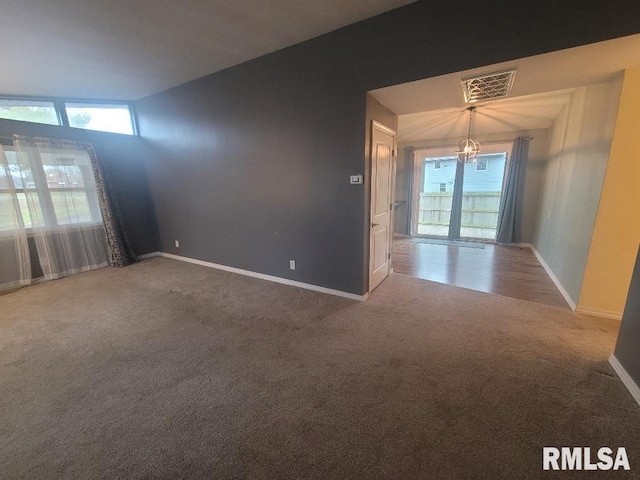 carpeted empty room with lofted ceiling and a notable chandelier