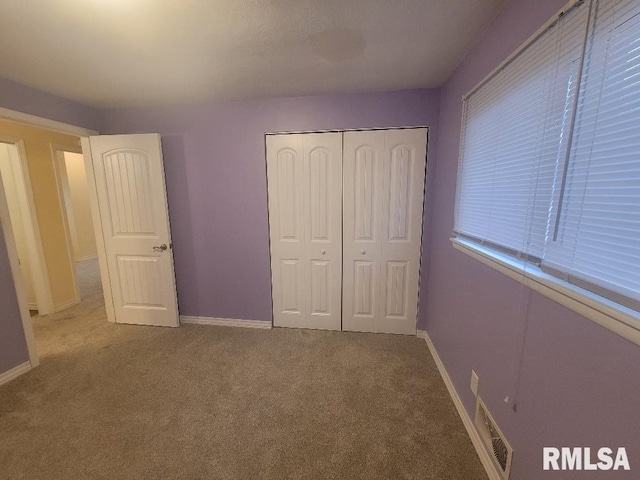 unfurnished bedroom with light carpet and a closet