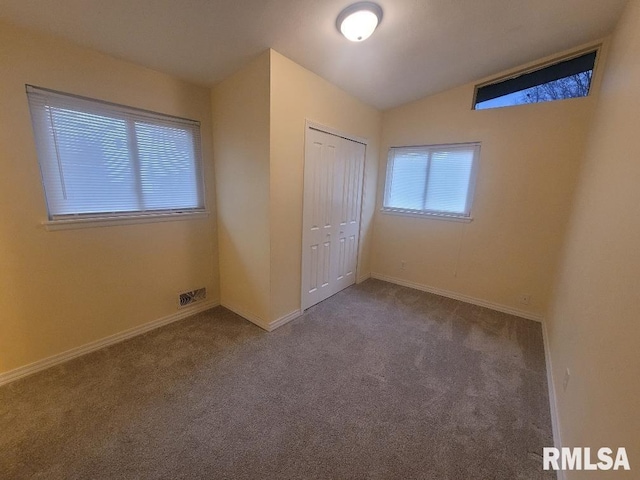 unfurnished bedroom featuring carpet flooring, lofted ceiling, and a closet