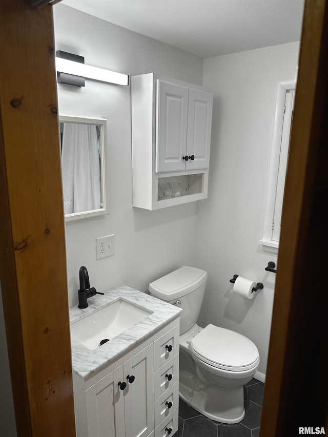 bathroom featuring tile patterned flooring, vanity, and toilet