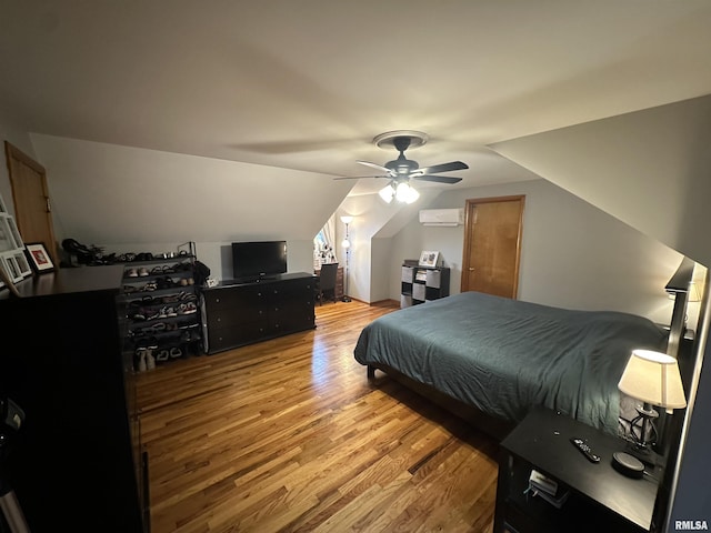 bedroom featuring vaulted ceiling, light hardwood / wood-style floors, a wall unit AC, and ceiling fan