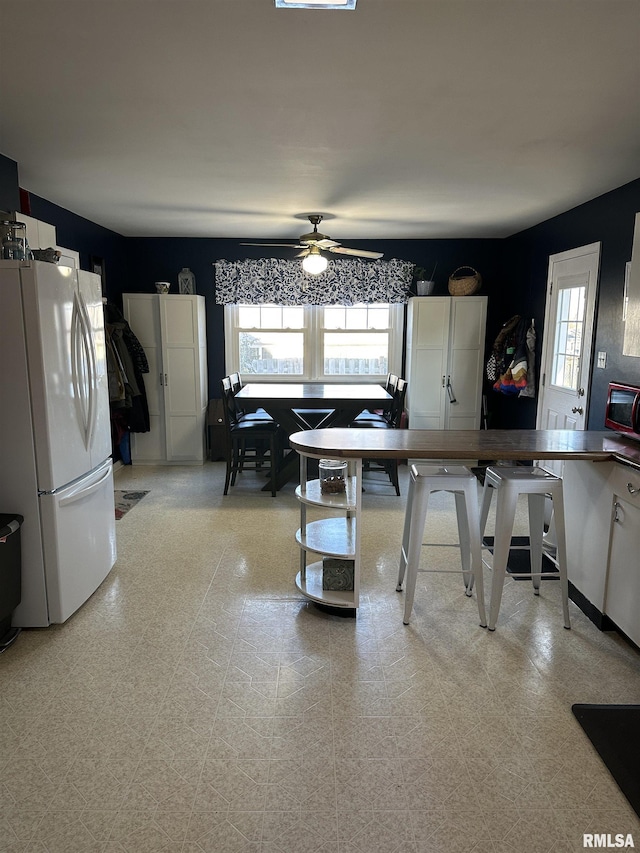 kitchen with ceiling fan, white fridge, and white cabinetry