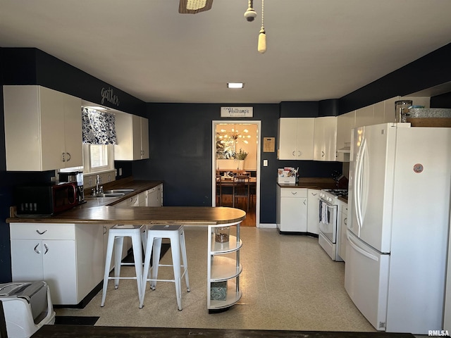 kitchen with wood counters, white appliances, white cabinets, sink, and kitchen peninsula