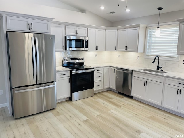 kitchen with light stone countertops, appliances with stainless steel finishes, tasteful backsplash, sink, and hanging light fixtures