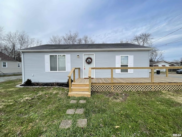 view of front facade with a wooden deck and a front lawn