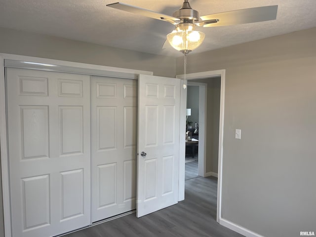 unfurnished bedroom featuring ceiling fan, dark hardwood / wood-style floors, a textured ceiling, and a closet