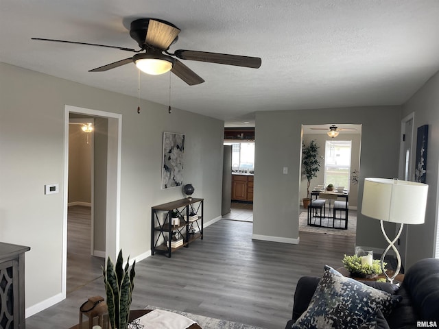 living room with a textured ceiling, dark hardwood / wood-style flooring, and ceiling fan