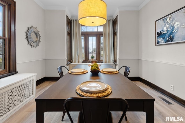 dining room with french doors, crown molding, radiator, and light hardwood / wood-style flooring