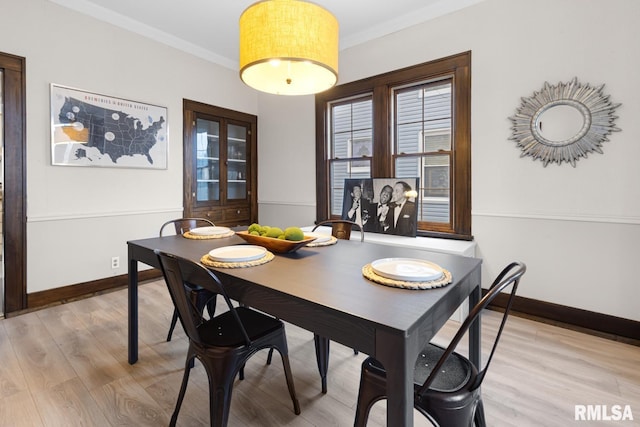 dining area with light wood-type flooring and ornamental molding