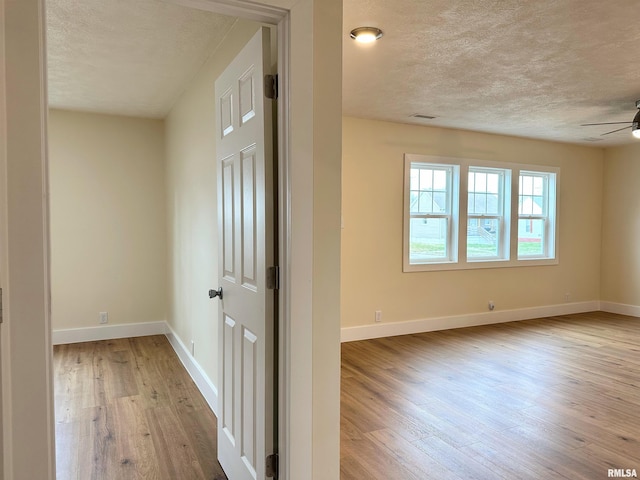 hallway featuring light hardwood / wood-style floors and a textured ceiling