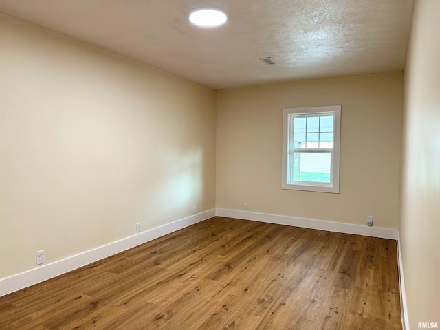 unfurnished room with a textured ceiling and light wood-type flooring