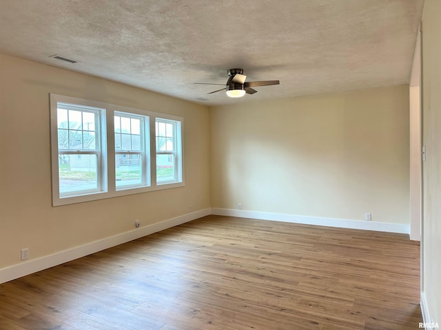 spare room featuring ceiling fan, light hardwood / wood-style floors, a healthy amount of sunlight, and a textured ceiling