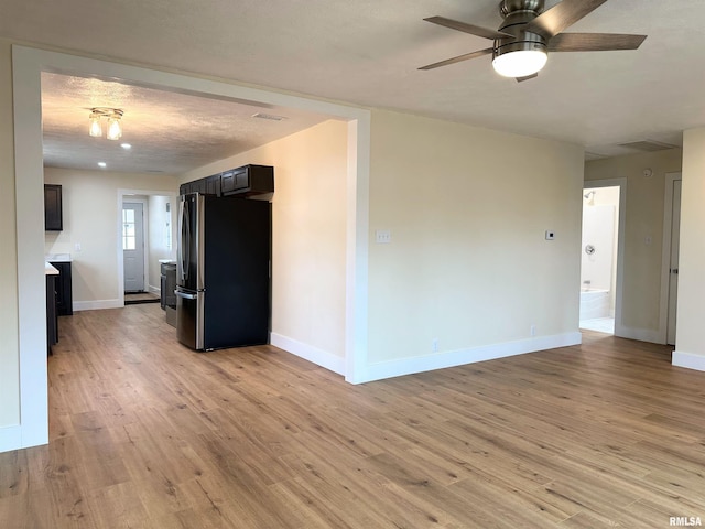 spare room with ceiling fan, a textured ceiling, and light wood-type flooring